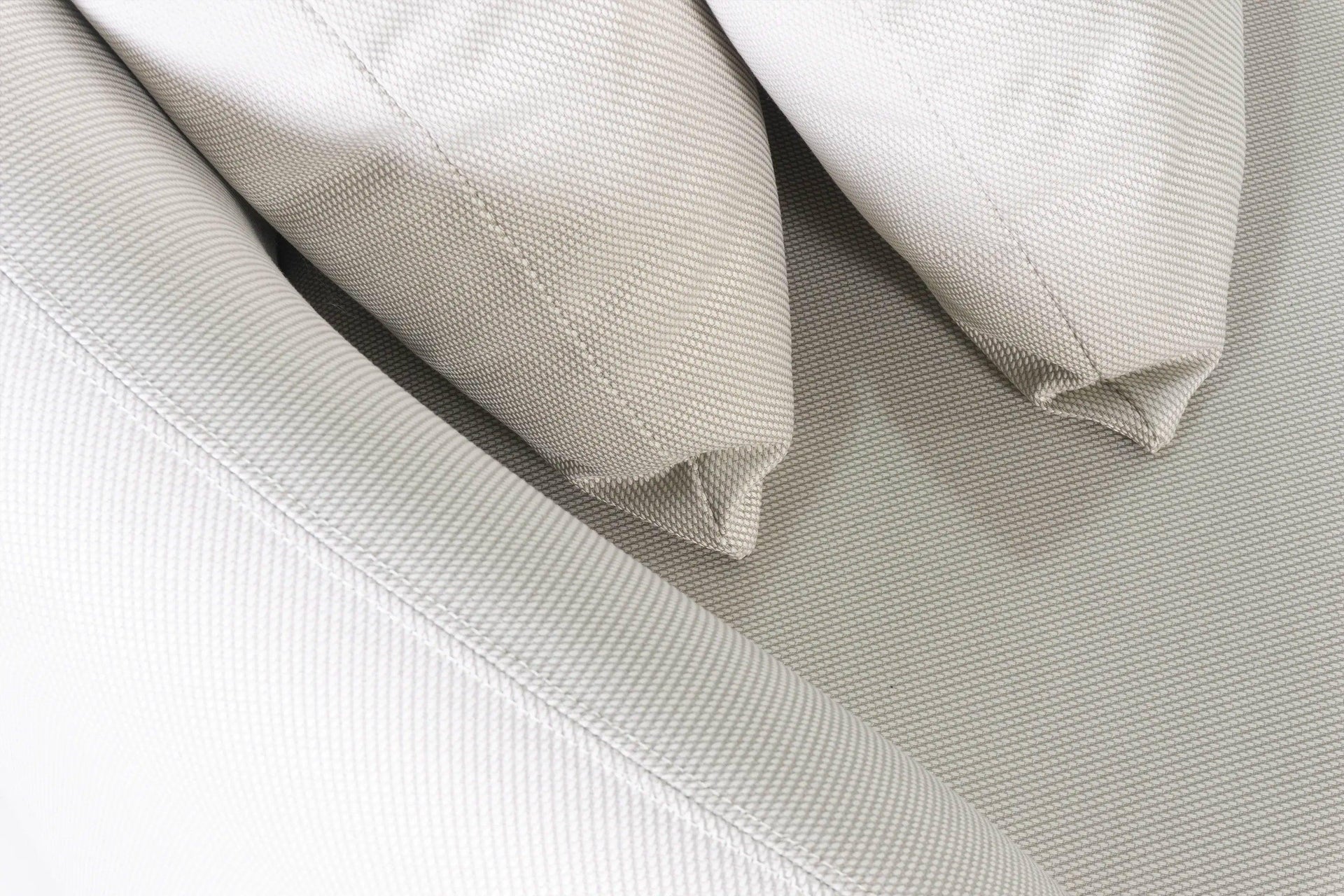 Nahaufnahme des Santorini Garten Loungesofa Sets (8-Sitzer) mit hellbeigem, gewebtem Polsterstoff. Zeigt feines, gitterartiges Gewebe und gestickte Nähte an den Kissenkanten, unterstreicht elegantes Outdoor-Design.