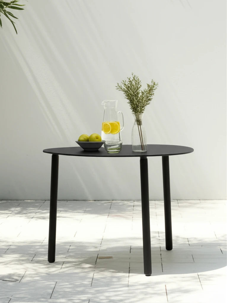 Valencia-S Lounge Beistelltisch aus Aluminium-Pulverbeschichtung mit runder Tischplatte, präsentiert im minimalistischen Setting mit grünen Äpfeln, Zitronenwasser und grüner Vase, auf Fliesenboden.
