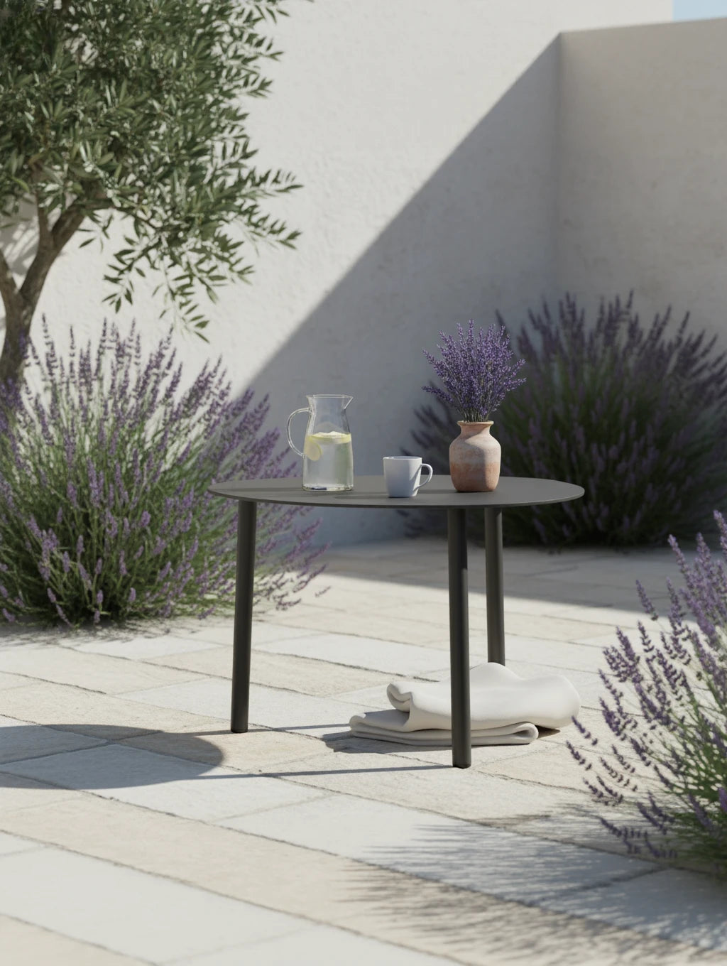 Valencia-S Lounge Beistelltisch aus Aluminium-Pulverbeschichtung, eiförmig, mit Glas und Deko auf dem Tisch, eingerahmt von Lavendel und Olivenbaum, auf mediterraner Terrasse angeordnet.
