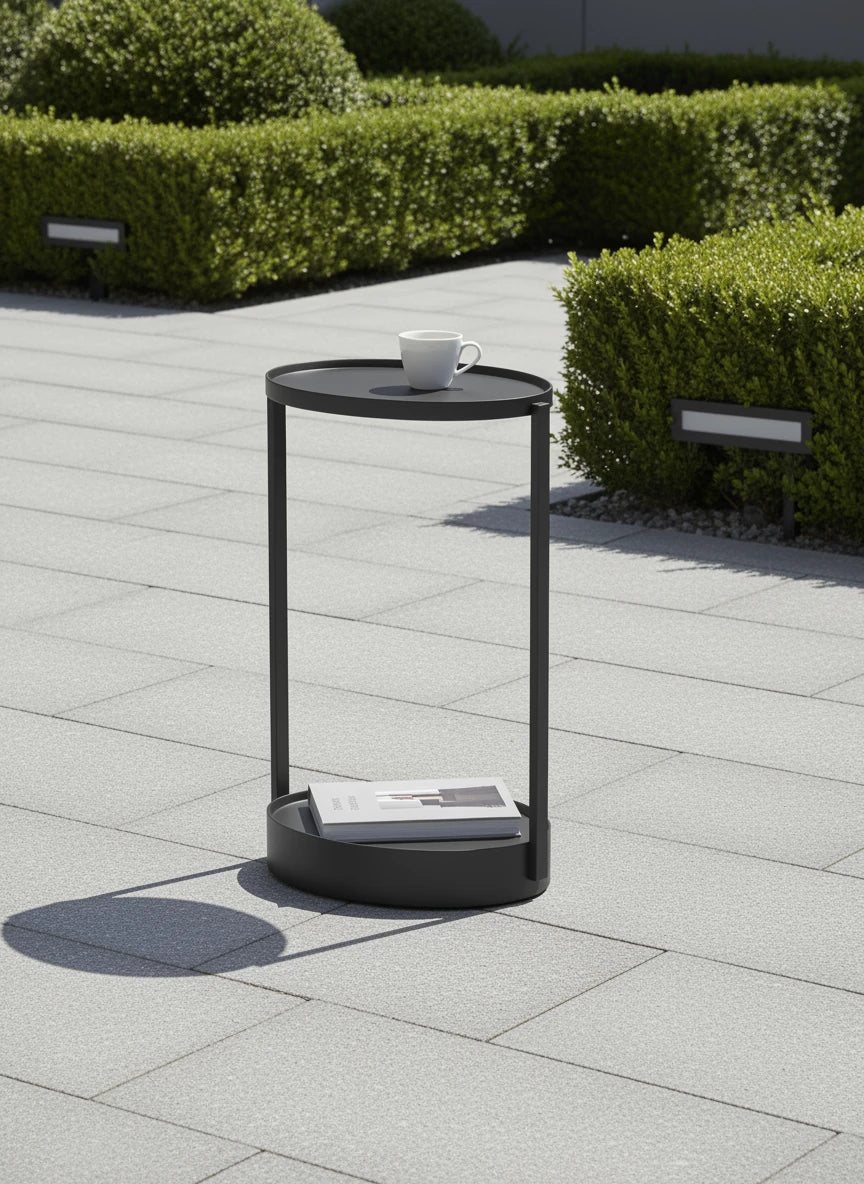 Rauma durchbrochener Couchtisch - Aluminium pulverbeschichtet, ein eleganter zweistufiger Tisch auf grauen Fliesen, mit einer Kaffeetasse und einem Buch, ideal für stilvolle Outdoor-Bereiche.