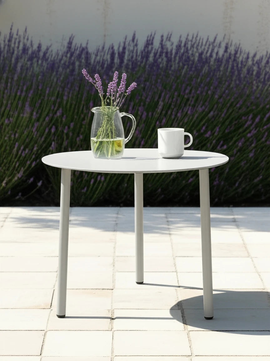 Der Valencia-S Lounge Beistelltisch aus Aluminium-Pulverbeschichtung steht auf einer Terrasse, dekoriert mit einem Glaswasserkrug und Lavendel. Ideal für stilvolle Outdoor-Momente.
