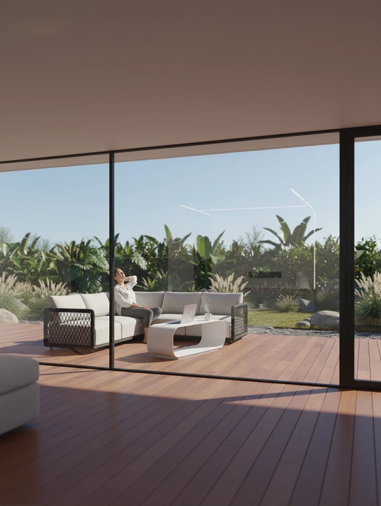 Das Mykonos Garten Ecklounge Set, 2er-Set, ist auf einem gemütlichen Holzdeck platziert. Eine Person lehnt sich entspannt auf dem L-förmigen Sofa zurück, genießt den Ausblick auf den tropischen Garten.