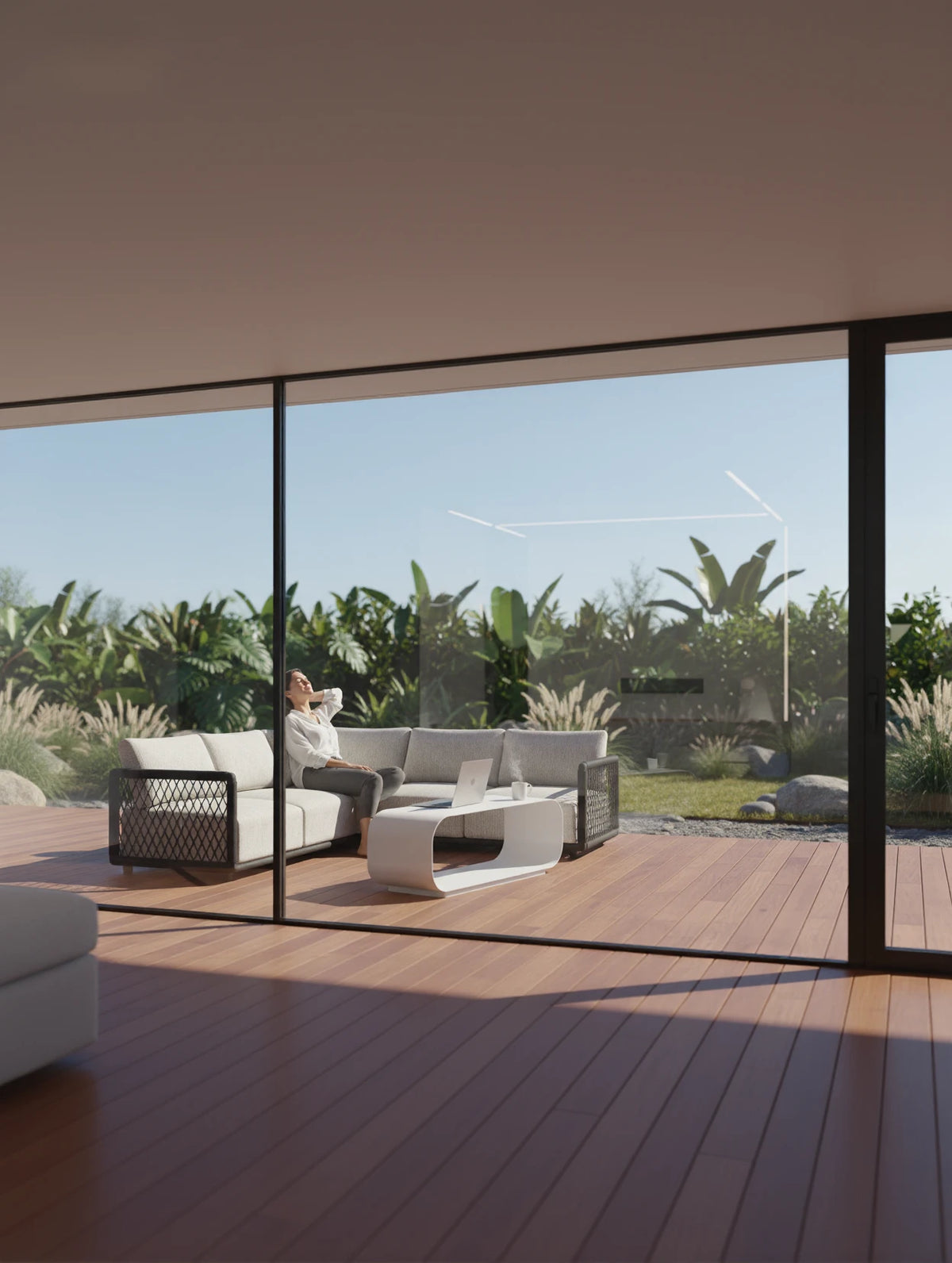 Das Mykonos Garten Ecklounge Set, 2er-Set, ist auf einem gemütlichen Holzdeck platziert. Eine Person lehnt sich entspannt auf dem L-förmigen Sofa zurück, genießt den Ausblick auf den tropischen Garten.