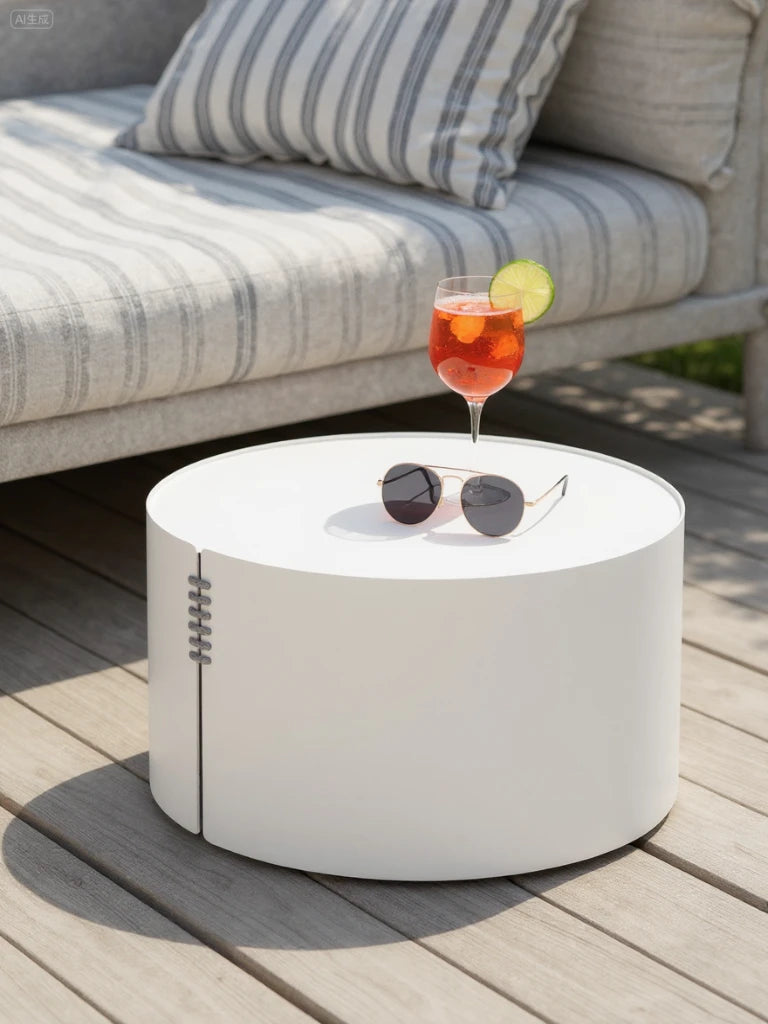 Speyer Säule Runder Couchtisch - Aluminium pulverbeschichtet-Weiß steht auf einer Holzterrasse neben einem Outdoor-Sofa, mit Sonnenbrille und Cocktail darauf, ideal für stilvolle, wetterfeste Outdoor-Gestaltungen von Finqa GmbH.
