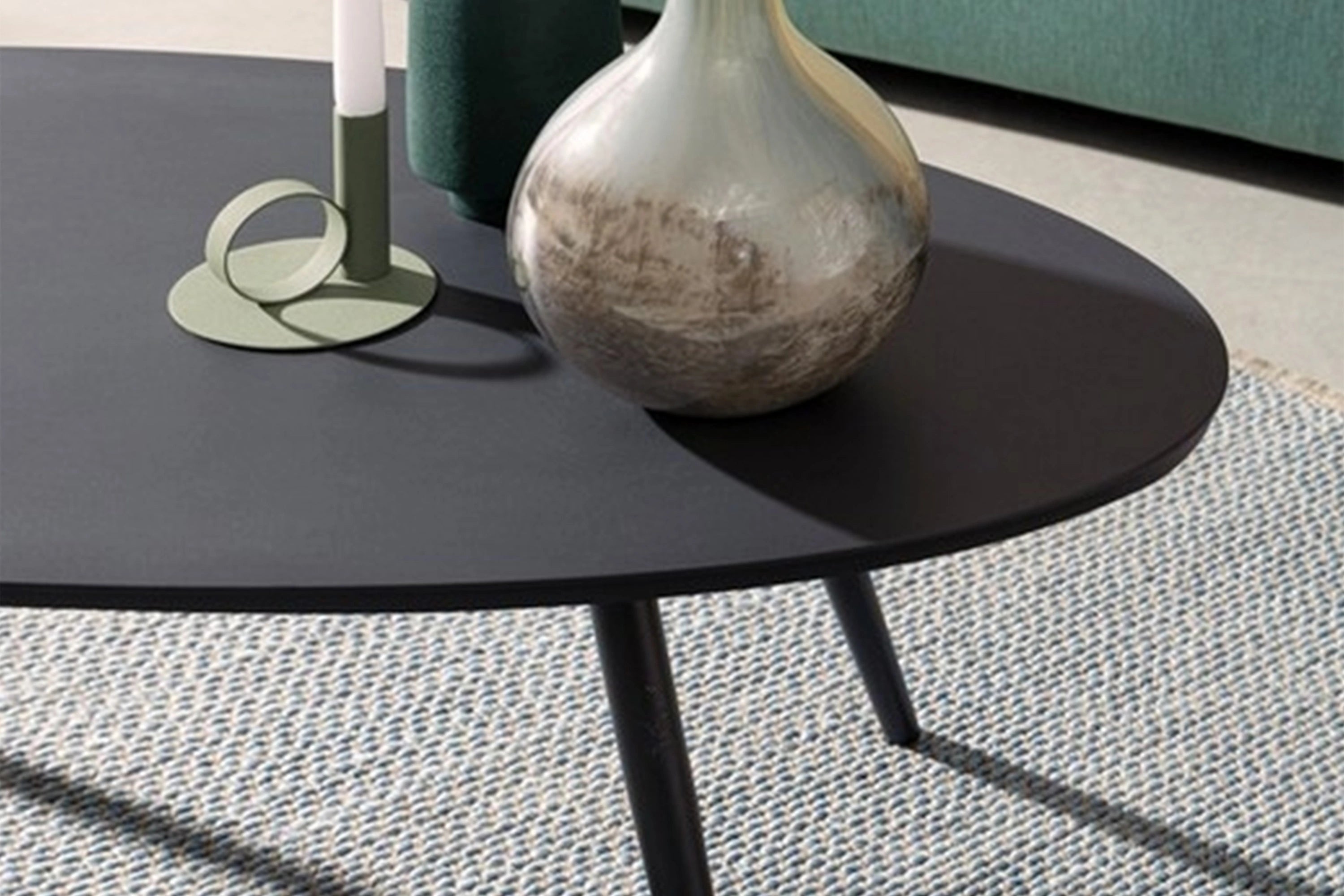 Freiburg Oval Boat Couchtisch - Aluminium pulverbeschichtet: Nahaufnahme eines runden, schwarzen Couchtisches mit einer Vase darauf, ideal für elegante und modulare Outdoor-Einrichtungen von Finqa GmbH.