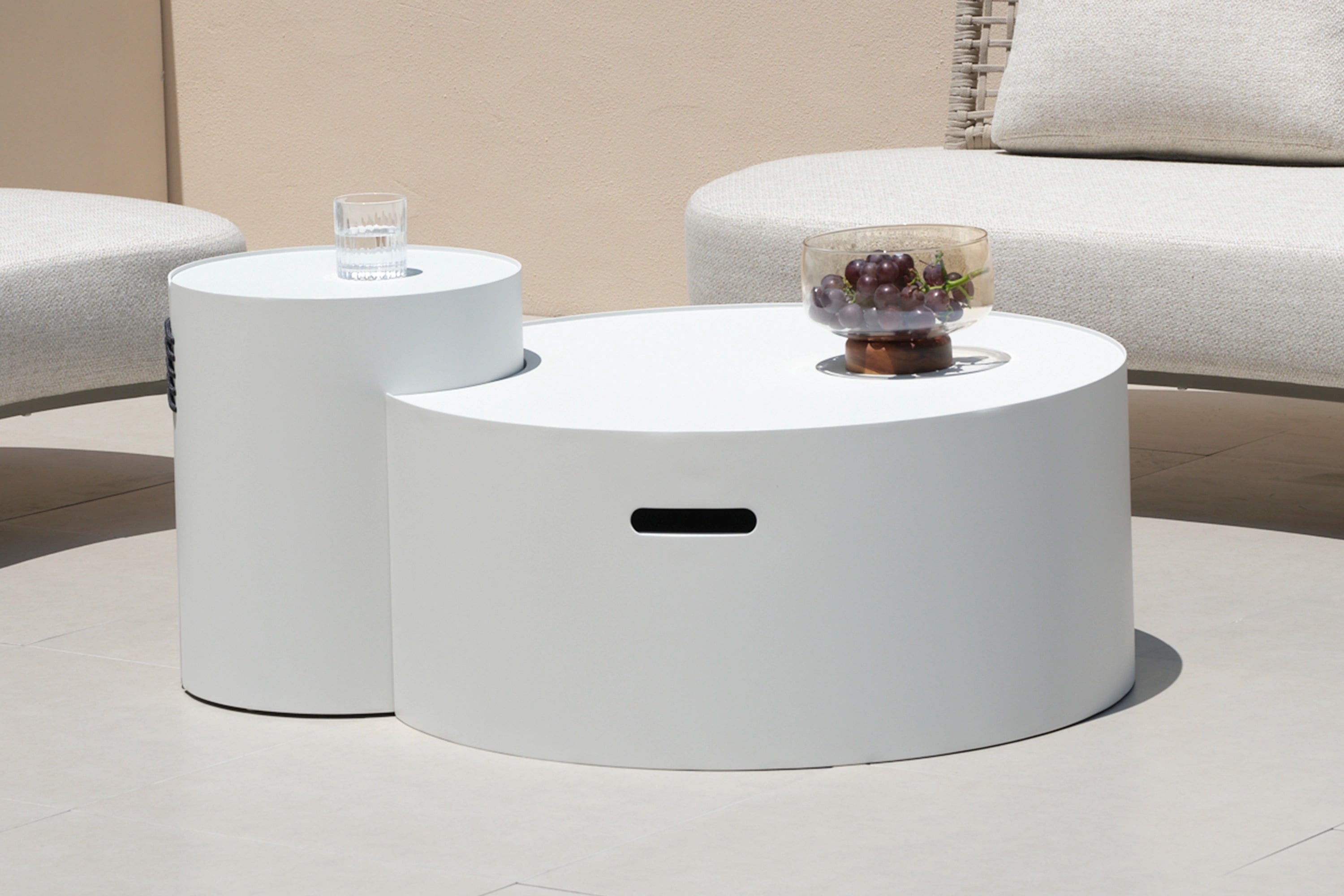 Aluminium runde Solarleuchte auf weißem Tisch mit Glas Wasser. Die multifunktionale Leuchte von Finqa GmbH kombiniert modernes Design mit Nachhaltigkeit, ideal für stilvolle Außenbereiche.