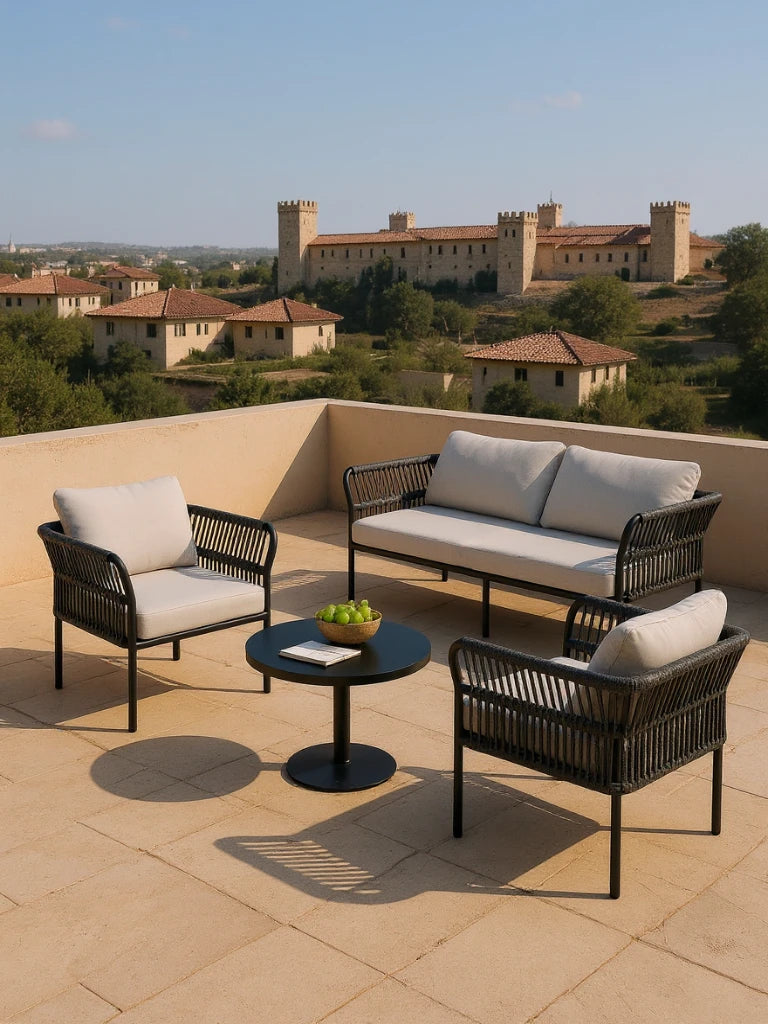 Malaga Garten Ecklounge Set (4-Sitzer) auf einem Terrassenbereich, bestehend aus zwei Einzelstühlen, einem Zweisitzer-Sofa und einem runden Tisch, alles auf schwarzem Metallrahmen mit gewebten Seiten und hellgrauen Kissen.