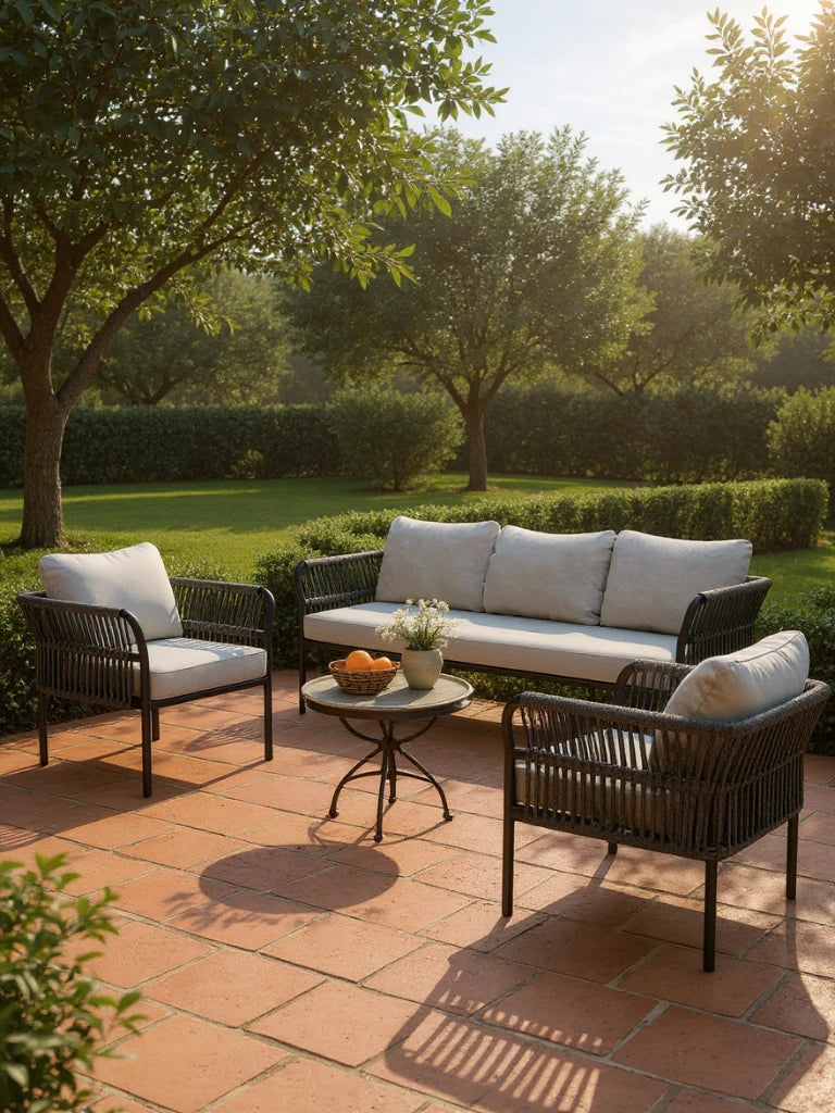 Malaga Garten Ecklounge Set (5-Sitzer) auf sonniger Terrasse, bestehend aus einem dreisitzigen Sofa, zwei Sesseln mit hellen Kissen und einem Metalltisch mit Früchten und Pflanzen.