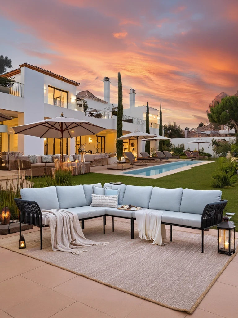 Malaga Garten Ecklounge Set (6-Sitzer) auf großer Terrasse, bestehend aus L-förmigem, wetterfestem Sofa mit weichen Kissen, flankiert von leuchtenden Laternen, ideal für stilvolles, komfortables Outdoor-Wohnen.