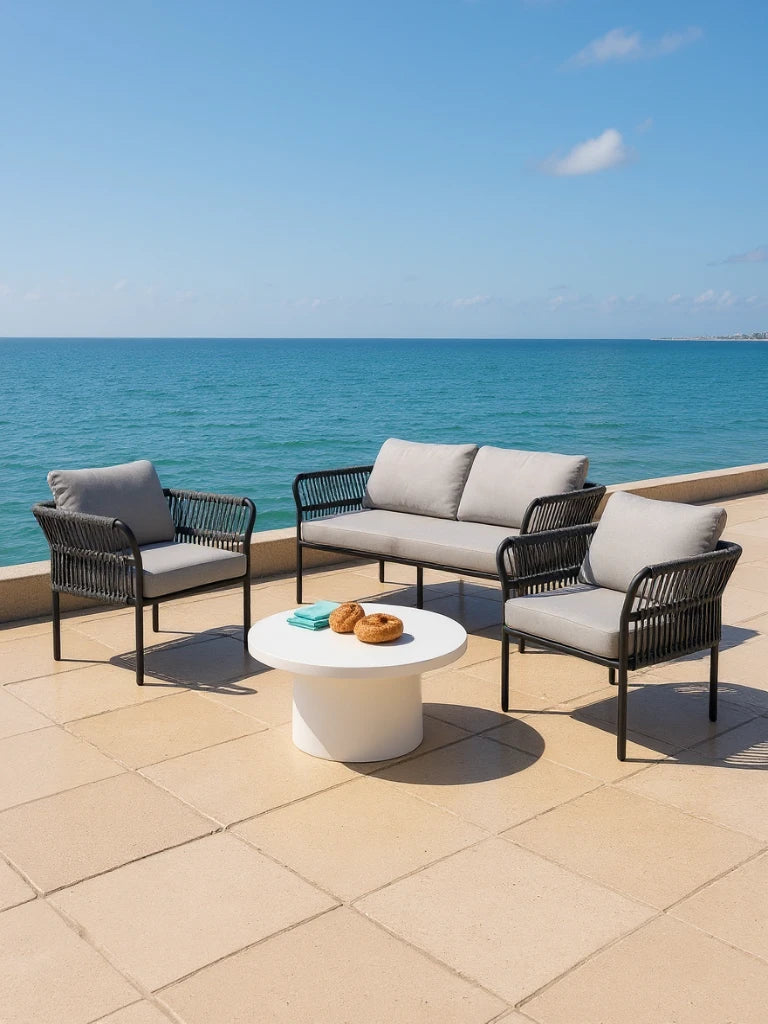 Malaga Garten Ecklounge Set (4-Sitzer) auf einer Terrasse, bestehend aus zwei schwarzen Sesseln und einem Zweisitzer-Sofa um einen weißen Tisch mit Backwaren, verkörpert stilvolle Outdoor-Entspannung.