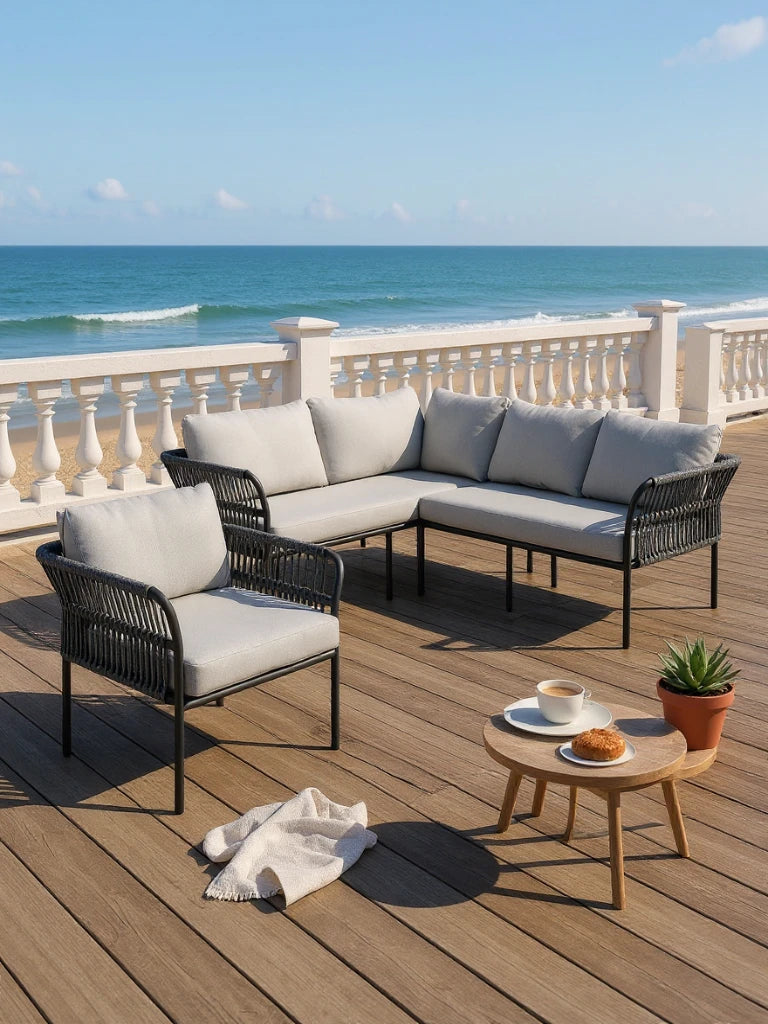 Malaga Garten Ecklounge Set (5-Sitzer) auf einer Terrasse, bestehend aus einem L-förmigen Sofa und einem Sessel mit geflochtenen Armlehnen, daneben ein runder Holztisch mit Kaffee und Gebäck.