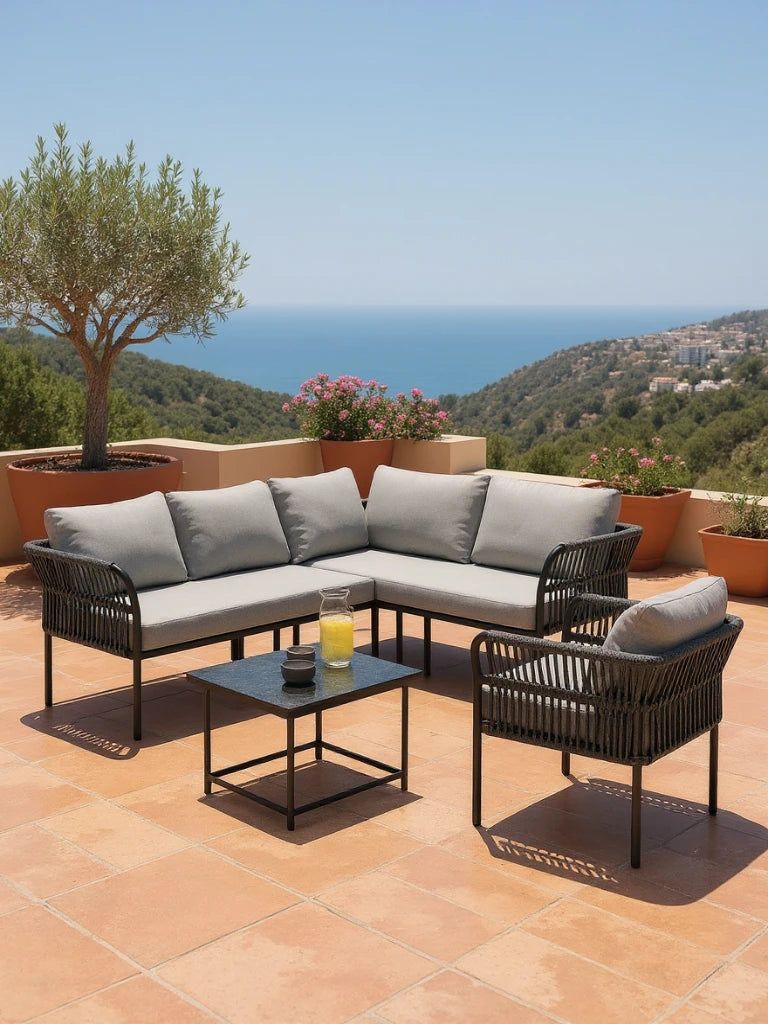 Malaga Garten Ecklounge Set (5-Sitzer) auf Terrasse mit L-förmigem Sofa und Sessel, umgeben von Terrakotta-Töpfen. Tisch mit Glaskaraffe und Bechern, bietet stilvolle Outdoor-Entspannung.