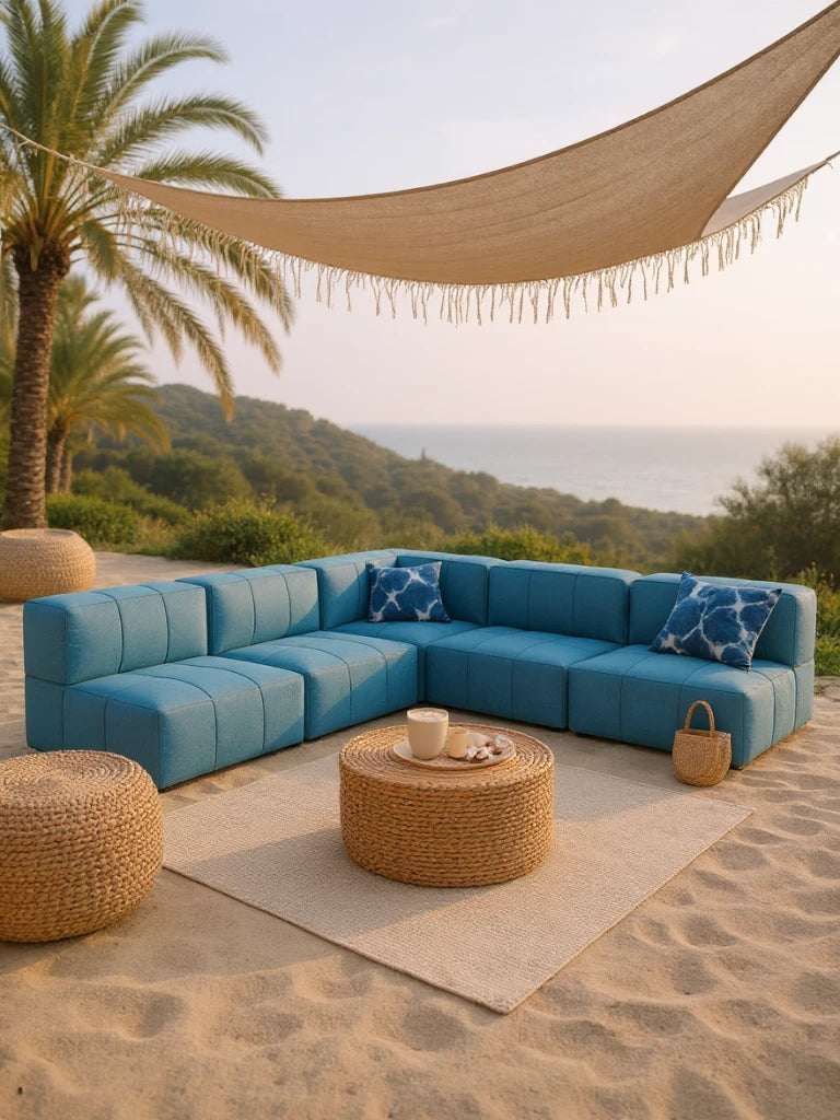 Modulares Garten-Lounge-Set Marshmallow, 5er-Set: Ein entspanntes Lounge-Setup am Strand mit einem L-förmigen Sofa, runden Rattan-Tisch und Poufs, unter einem Sonnenschutz, inspiriert von Kindheitserinnerungen.