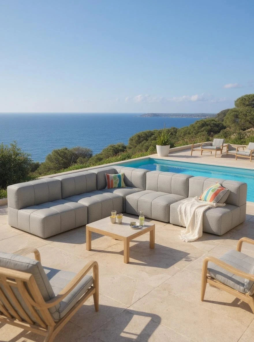 Modulares Garten-Lounge-Set Marshmallow, 5er-Set auf einer Terrasse, bestehend aus einem L-förmigen grauen Sofa und Holztisch vor einem Pool mit Meerblick.