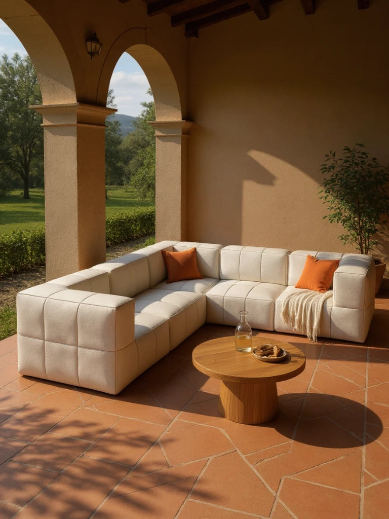 Modulares Garten-Lounge-Set Marshmallow, 5er-Set auf mediterraner Terrasse mit L-förmigem Sofa, terrakottafarbenem Boden, Holztisch mit Wasserkarafe und Gebäck, flankiert von Pflanzen und Gartenblick durch Bögen.