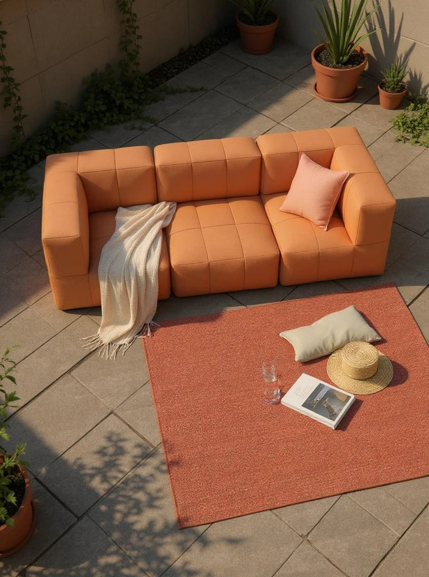 Modulares Garten-Lounge-Set Marshmallow, 3er-Set: Terracotta-Sofa auf Steinplatten, mit Kissen, Decke, Teppich, Buch und Gläsern, umgeben von Pflanzen in Terrakotta-Töpfen; ideal für entspannte Outdoor-Momente.