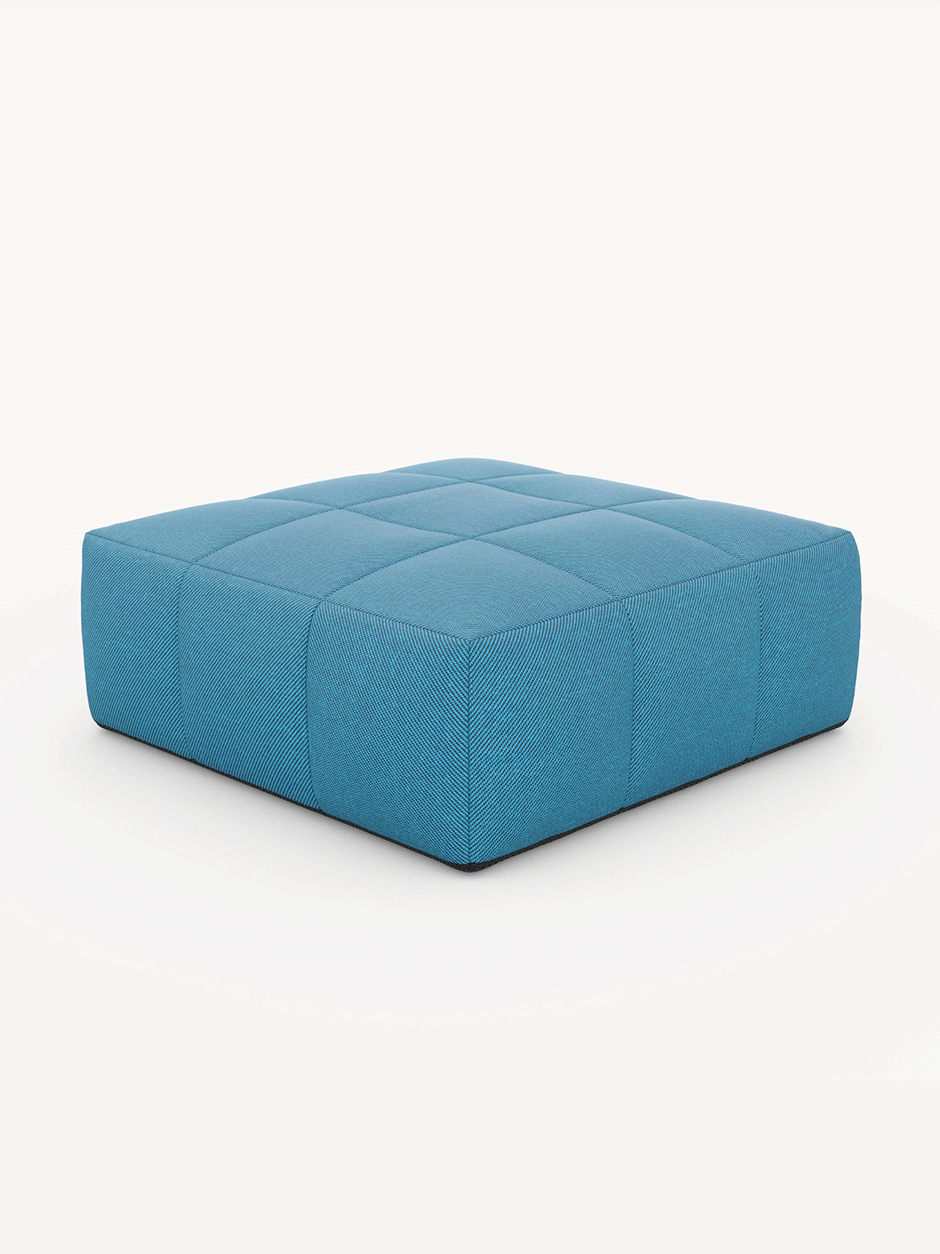 Marshmallow Bonbon Ottoman, ein quadratischer, niedrigprofiliger Pouf mit gepolstertem Kachelmuster, inspiriert von Kindheitserinnerungen, bietet vielseitige Einsatzmöglichkeiten als Fußstütze oder Couchtischersatz.