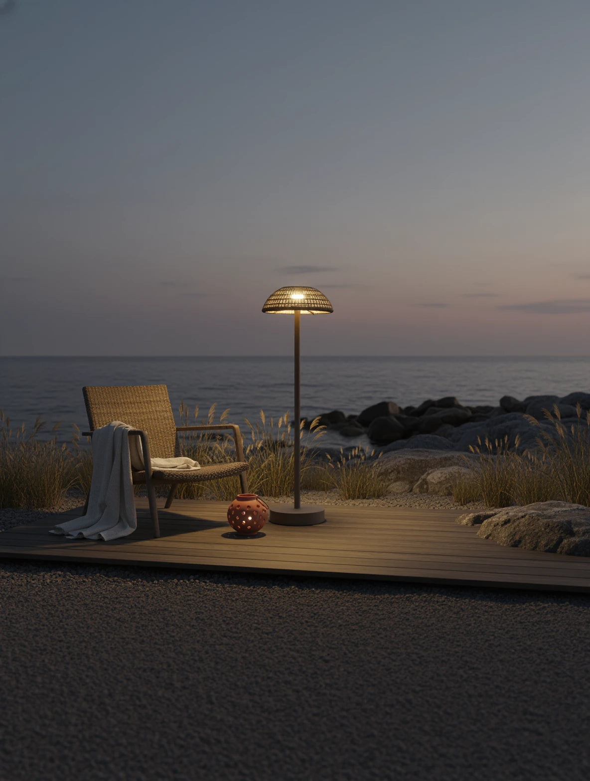 Kapalai Vertikale Lampe Aluminium Pulverbeschichtung Olefin- Taupe steht auf einem Holzdeck am Strand, beleuchtet sanft die Umgebung und ergänzt die entspannende Atmosphäre mit ihrer eleganten, wetterfesten Bauweise.