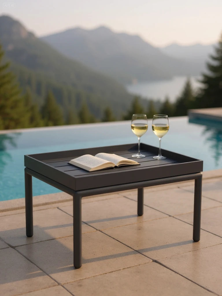 Amsterdam Lounge-Lodi Aluminium-Couchtisch auf einer Terrasse neben einem Pool, trägt ein Tablett mit Buch und zwei Weingläsern, ideal für stilvolle und funktionale Outdoor-Umgebungen.