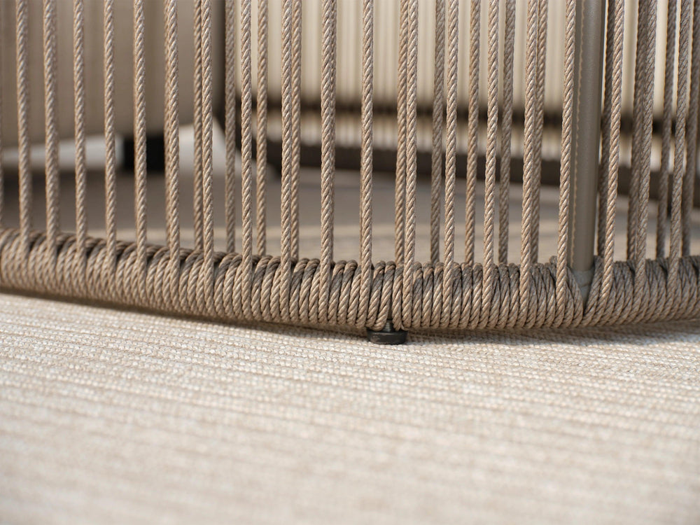 Nahaufnahme des Kapalai Garten Loungesofa Sets (5-Sitzer), das mit vertikal gewickelten, beigen Seilen um einen Metallrahmen gestaltet ist, auf einem neutralen, gewebten Teppich sitzend.