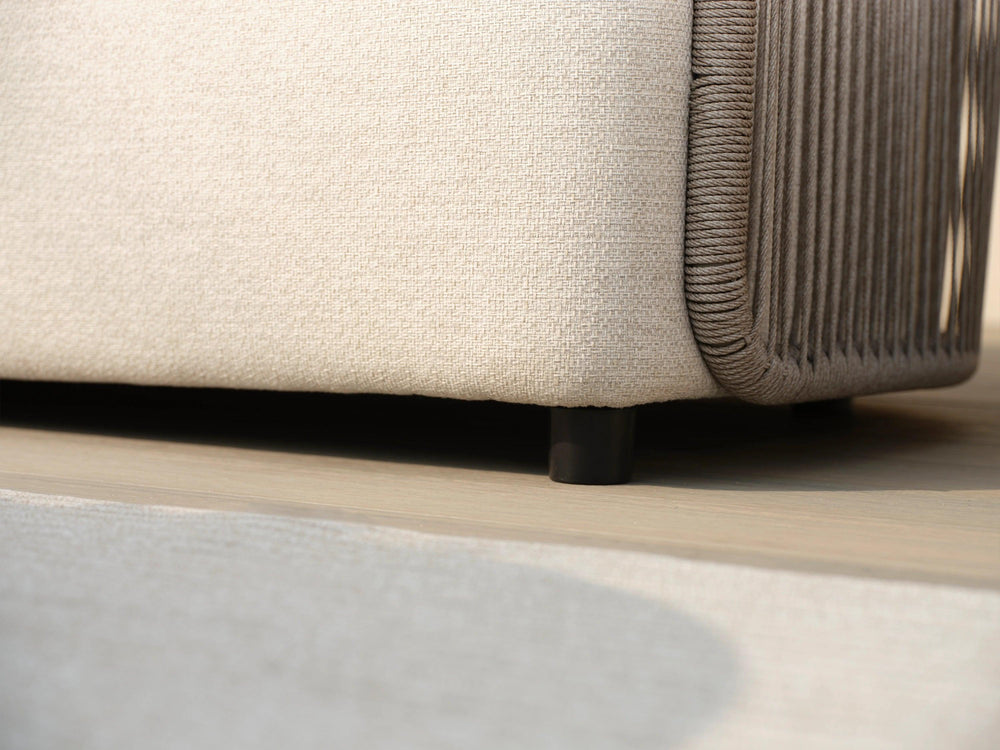 Nahaufnahme des Kapalai Garten Loungesofa Sets (5-Sitzer) mit hellbeigem, eng gewebtem Stoff, dekorativen taupefarbenen Seilsträngen und kurzem schwarzen Bein auf hellem Holzboden und Teppich.