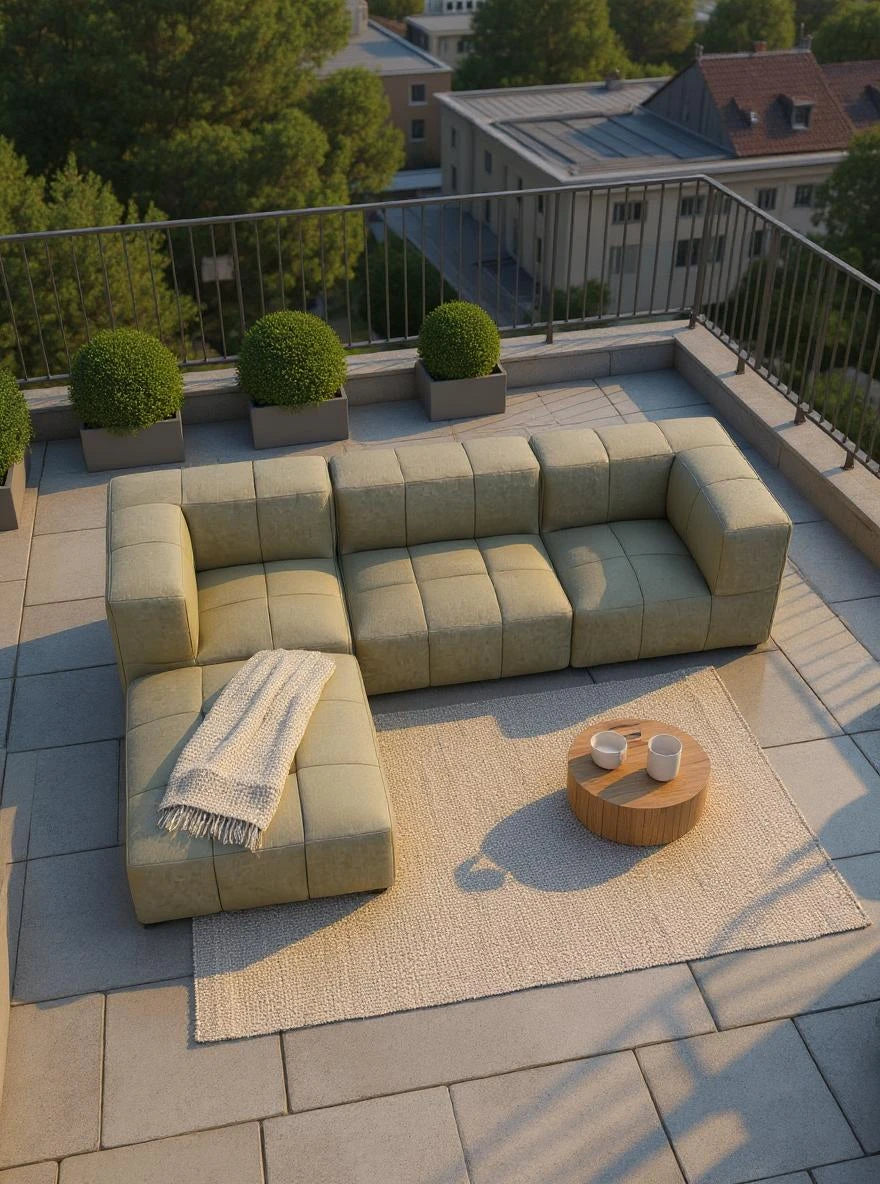 Babymax, 4er-Set (Copy): L-förmiges, modular aufgebautes Sofa in Salbeigrün, mit einer Chaiselongue. Auf einem Holztisch stehen zwei weiße Keramikbecher, umgeben von gepflegten Sträuchern in quadratischen Pflanzgefäßen.