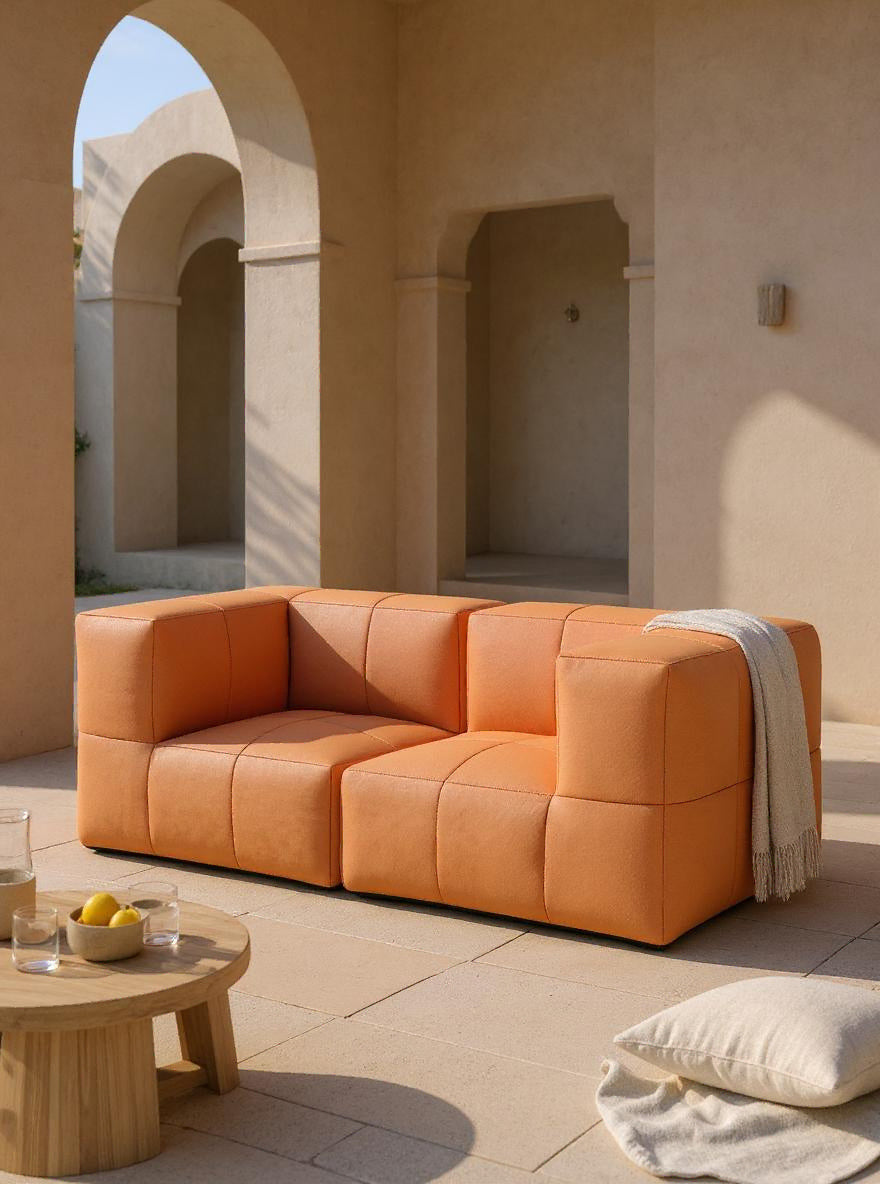 Marshmallow Modular Sofa Set S auf einem Holztisch mit einer Schale Zitronen und einem Glas Wasser. Dieses Sofa inspiriert von Kindheitserinnerungen bietet modularen Komfort und nachhaltiges Design für stilvolle Außenbereiche.
