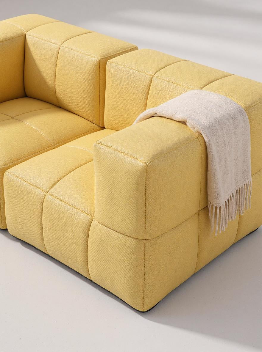 Marshmallow Modular Sofa Set S: Nahaufnahme eines gelben Sofas mit weißer Decke, inspiriert von Marshmallows, bietet es modulare Gestaltungsmöglichkeiten und nachhaltige Materialien, perfekt für individuelle Lounge-Designs.