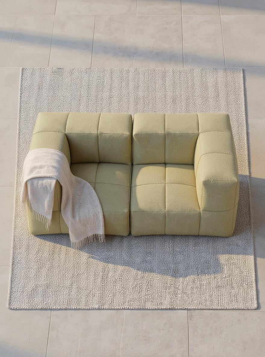 Nahaufnahme des Marshmallow Modular Sofa Set S, das auf einem Teppich steht. Ein modulares Sofa von Finqa GmbH, inspiriert von Marshmallows, ideal für individuelle Loungedesigns. Blanket auf Sofaarm sichtbar.