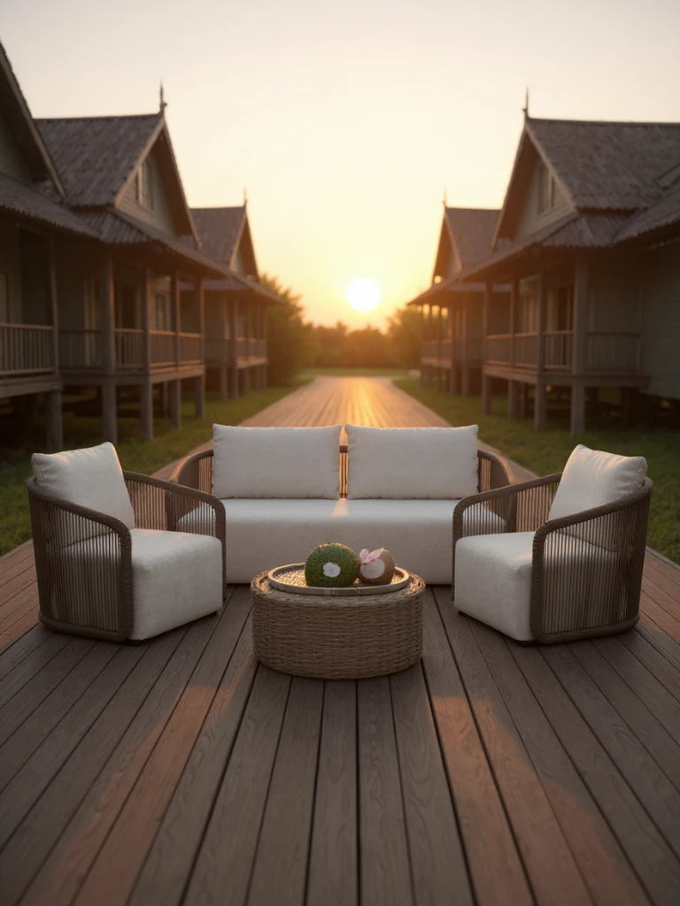 Kapalai Garten Loungesofa Set (4-Sitzer) auf einer Holzterrasse. Zwei-Sitzer-Sofa mit geflochtenem Rahmen und hellen Kissen, flankiert von passenden Sesseln und einem runden Rattan-Couchtisch.
