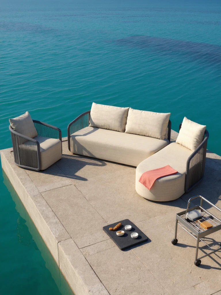 Kapalai Garten Loungesofa Set (5-Sitzer) auf Pier am Meer: Beige Sofa-Gruppe aus Sessel, Zweisitzer und Chaise-Lounge mit Korallenwurf, begleitet von Servierwagen und Frühstückstablett für entspannten Outdoor-Genuss.