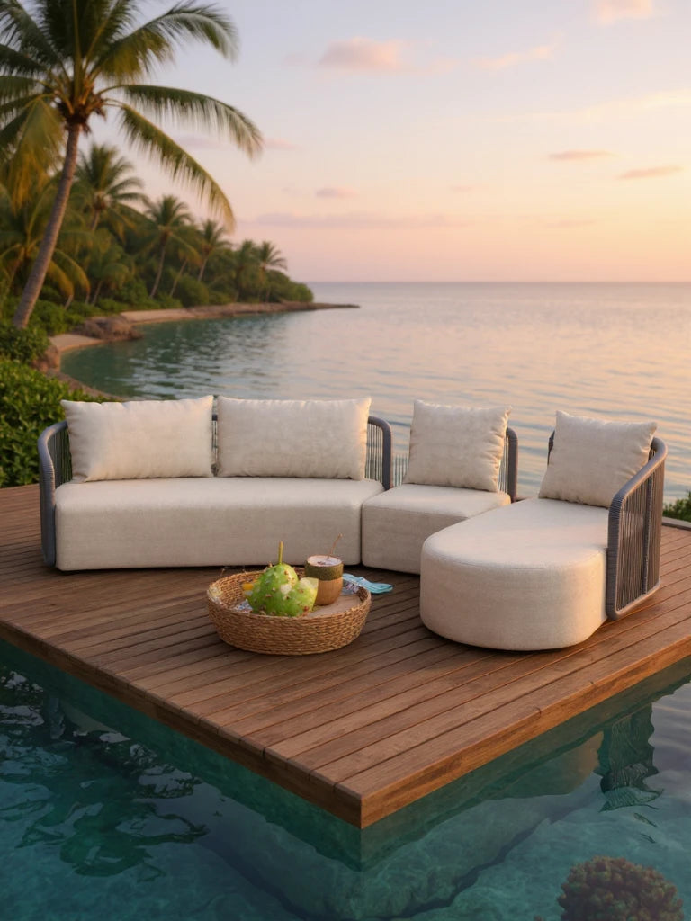 Kapalai Garten Loungesofa Set (5-Sitzer) auf einem schwimmenden Holzdeck, mit modularen, beigen Polstern, inklusive Ottoman und geschwungenem Chaiselongue, in tropischem Ambiente bei Sonnenuntergang, mit dekorativem Tablett.