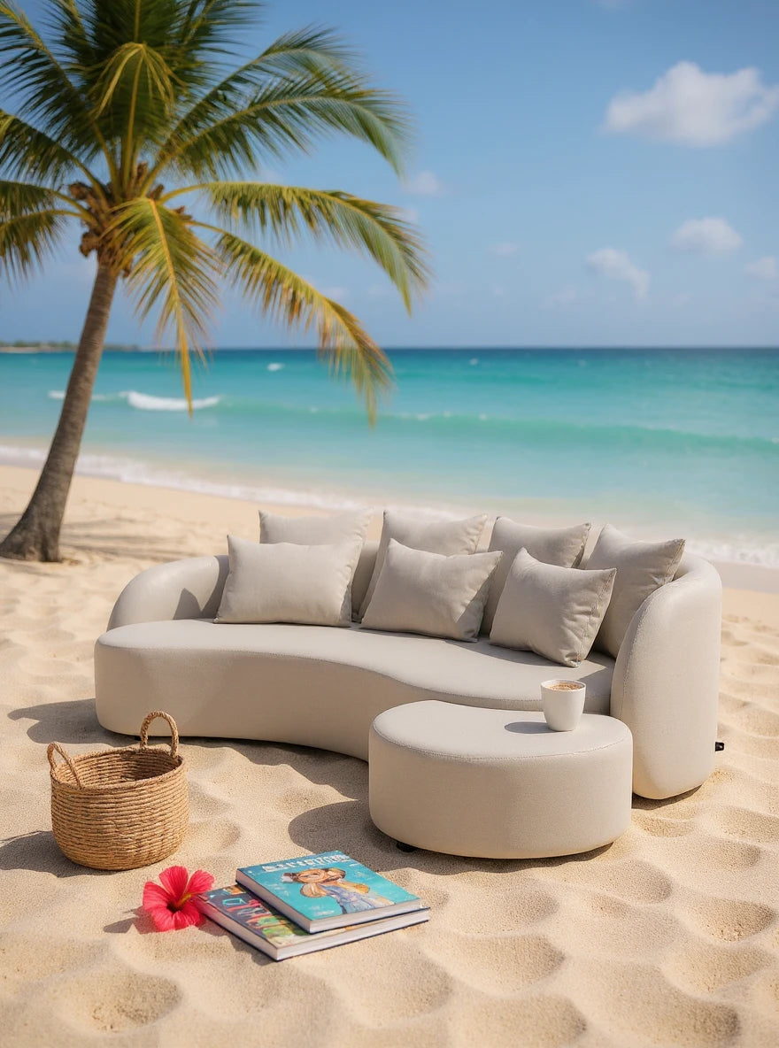 Das Santorini Garten Loungesofa Set (3-Sitzer) zeigt sich elegant am Strand mit geschwungenem Design, passenden Kissen und einem runden Ottoman. Perfekt für stilvolle und komfortable Outdoor-Entspannung.