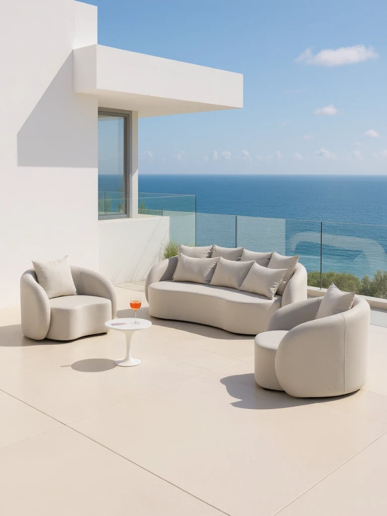 Santorini Garten Loungesofa Set (4-Sitzer) auf minimalistischer Terrasse, bestehend aus einem geschwungenen Sofa und zwei Sesseln, begleitet von einem weißen Beistelltisch mit Getränk, vor ruhigem Meerblick.