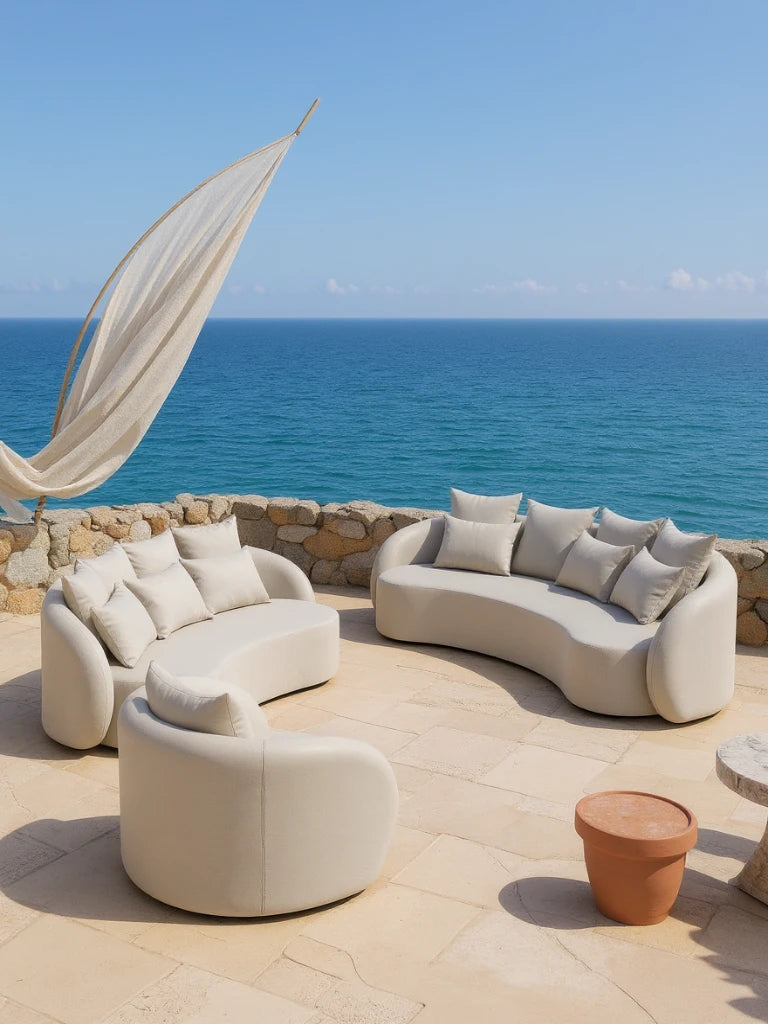 Santorini Garten Loungesofa Set (6-Sitzer) auf einer Terrasse am Meer, mit geschwungenen, cremefarbenen Lounge-Sitzen und Sofas in Halbkreisform, ergänzt durch hochwertige Kissen, ideal für flexible Outdoor-Gestaltung.